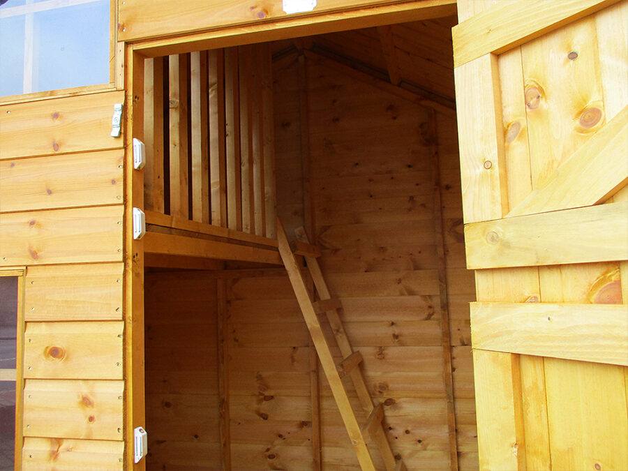 The interior of a wooden two storey Cottage Playhouse showcasing ladder access to a wooden balcony