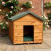 A side angle of a wooden dog kennel with a felt roof and access hole at the front on the structure, situated outside in a showroom on a brick floor