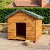 The side wall of a wooden dog kennel with a felt roof and access hole at the front on the structure, situated outside in a showroom on a brick floor