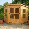 A wooden Standard Corner Summerhouse with central double doors and windows at the side on a slabbed section of a garden