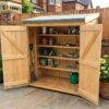 Dark stained wooden bike shed with double doors in a garden — Rutland Sheds