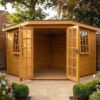 Wooden Georgian corner summerhouse with five-sided bay shape and French doors open, surrounded by flower borders in a walled garden – Rutland Sheds