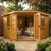 Georgian corner summerhouse with open French doors showing a relaxation interior with sofa, side table and garden plants, in a flower-filled walled garden – Rutland Sheds