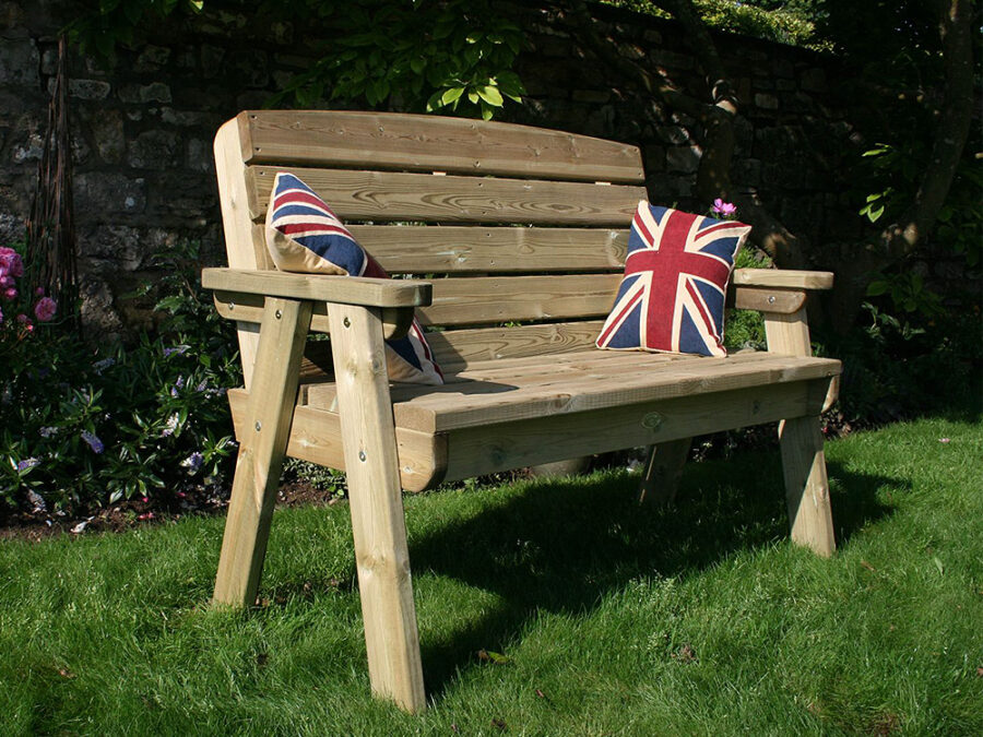 A Hutton Dean 2 Seater wooden garden furniture, with union flag pillows in a garden setting