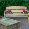 A Hutton Dean 2 Seater wooden garden furniture, with union flag pillows and a display wooden table infront of the seat on a gravel section in a garden setting