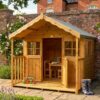 A modern Standard Playhouse with 2 windows either side of a front facing stable door with the top section open, with a wooden porch balcony and safety railings to the side of the structure