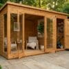Contemporary summerhouse interior with bifold doors open, showing sitting room area with armchair and adjacent garden tool storage section – Rutland Sheds